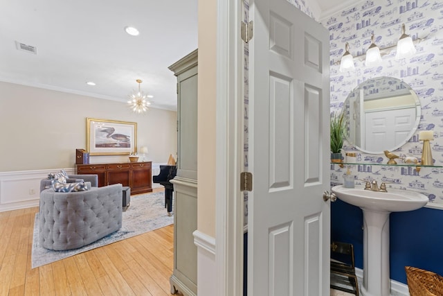 bathroom featuring visible vents, a wainscoted wall, ornamental molding, hardwood / wood-style floors, and wallpapered walls