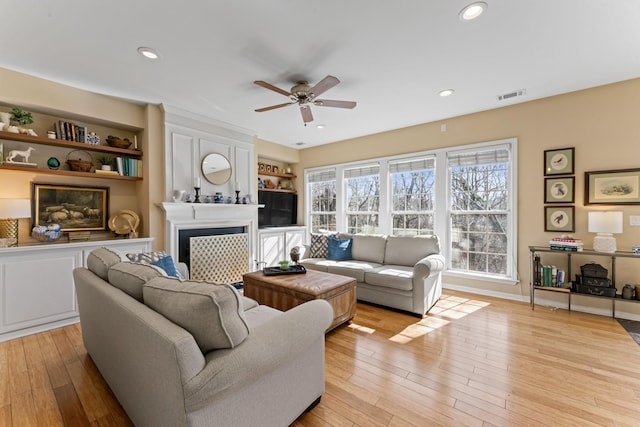 living room featuring recessed lighting, visible vents, a large fireplace, and light wood finished floors