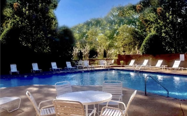 pool with a patio area and fence