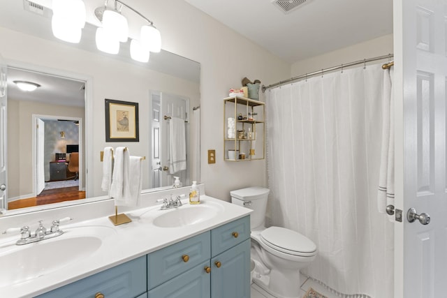 bathroom featuring double vanity, visible vents, toilet, and a sink