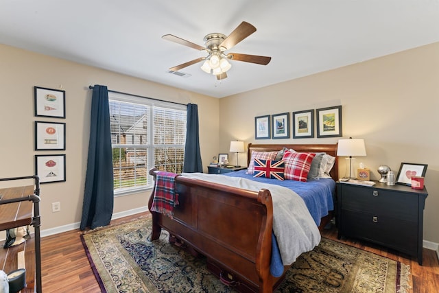 bedroom with ceiling fan, visible vents, baseboards, and wood finished floors