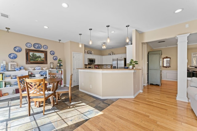 kitchen with visible vents, white cabinetry, stainless steel appliances, light wood finished floors, and ornate columns