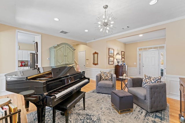 sitting room featuring a notable chandelier, visible vents, light wood finished floors, and a wainscoted wall