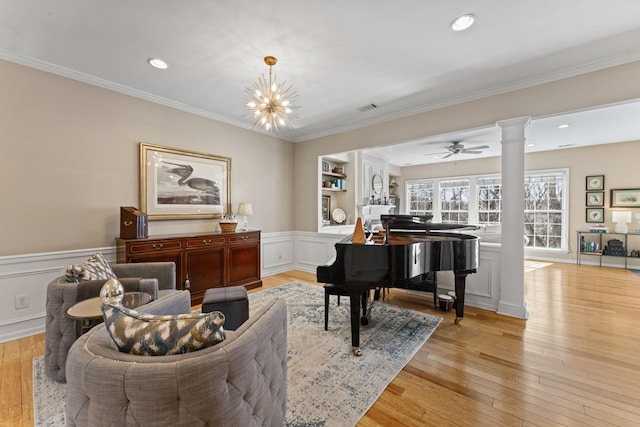 living area with wainscoting, light wood-style floors, ornate columns, and ornamental molding