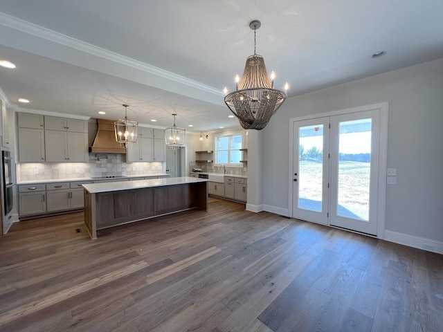 kitchen featuring a spacious island, tasteful backsplash, a chandelier, and custom range hood