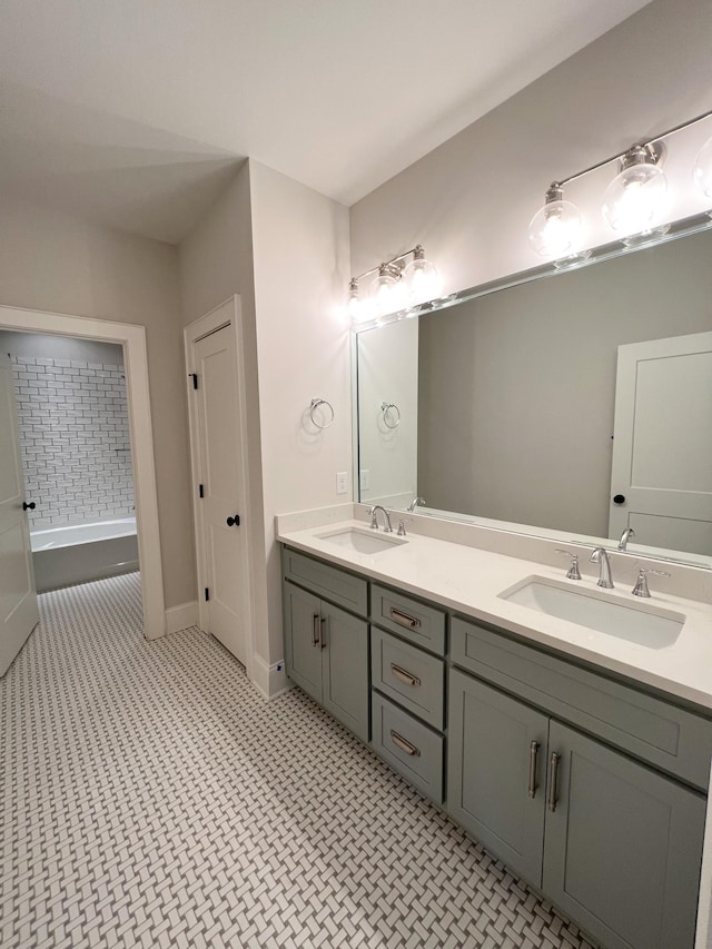 full bath with a sink, baseboards, a bath, and double vanity