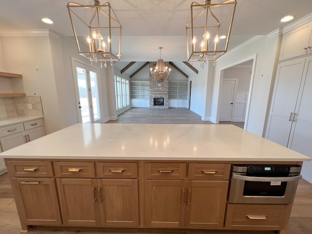 kitchen with open floor plan, a fireplace, crown molding, stainless steel oven, and a chandelier