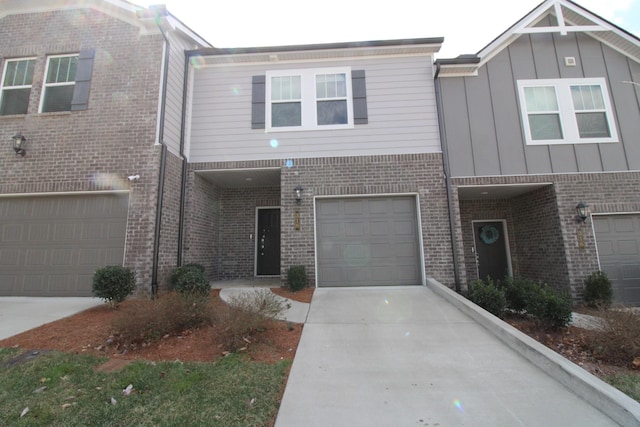 view of property with board and batten siding, concrete driveway, brick siding, and a garage