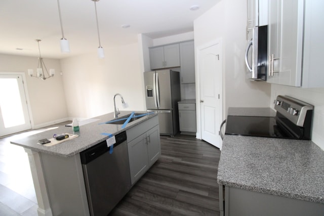 kitchen with dark wood finished floors, a kitchen island with sink, gray cabinets, a sink, and appliances with stainless steel finishes