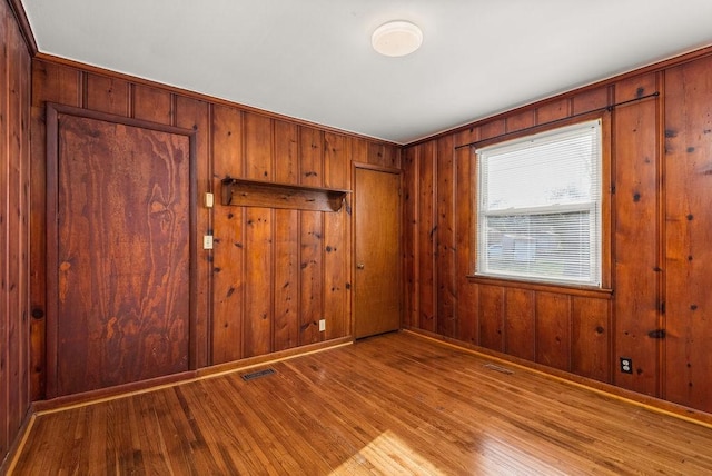 empty room featuring wood finished floors, visible vents, and baseboards