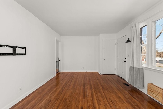 unfurnished room with visible vents, baseboards, and wood finished floors