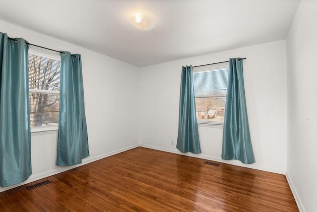 spare room with visible vents, baseboards, and wood finished floors