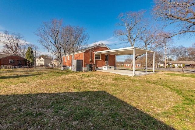 exterior space featuring an attached carport, a yard, brick siding, and a patio