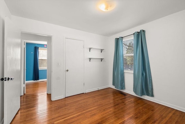 empty room featuring visible vents, baseboards, and wood finished floors