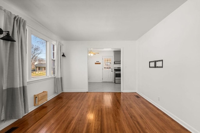 spare room with wood finished floors, visible vents, and baseboards