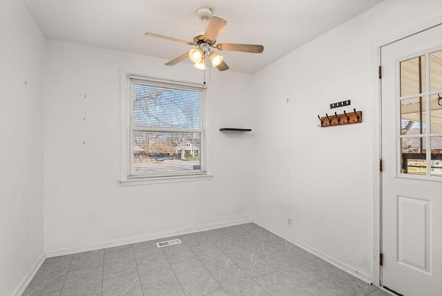 empty room with baseboards, visible vents, and ceiling fan