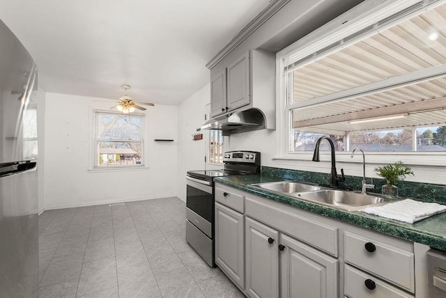 kitchen with gray cabinets, a sink, stainless steel appliances, under cabinet range hood, and dark countertops