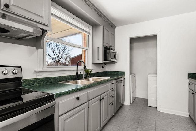 kitchen featuring dark countertops, extractor fan, appliances with stainless steel finishes, light tile patterned flooring, and a sink