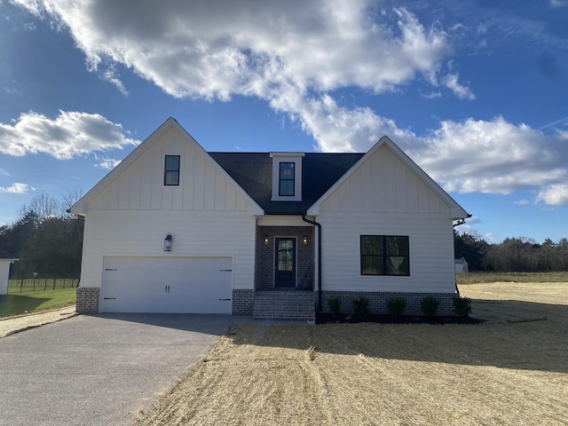 modern farmhouse style home with board and batten siding, an attached garage, brick siding, and driveway