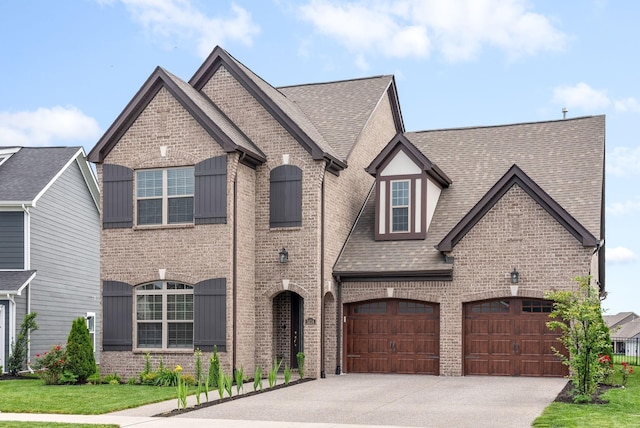 french country home with concrete driveway, brick siding, and roof with shingles