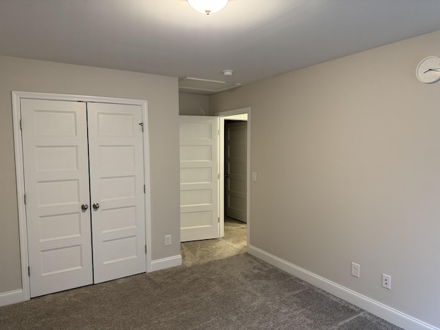 unfurnished bedroom with a closet, baseboards, and dark carpet