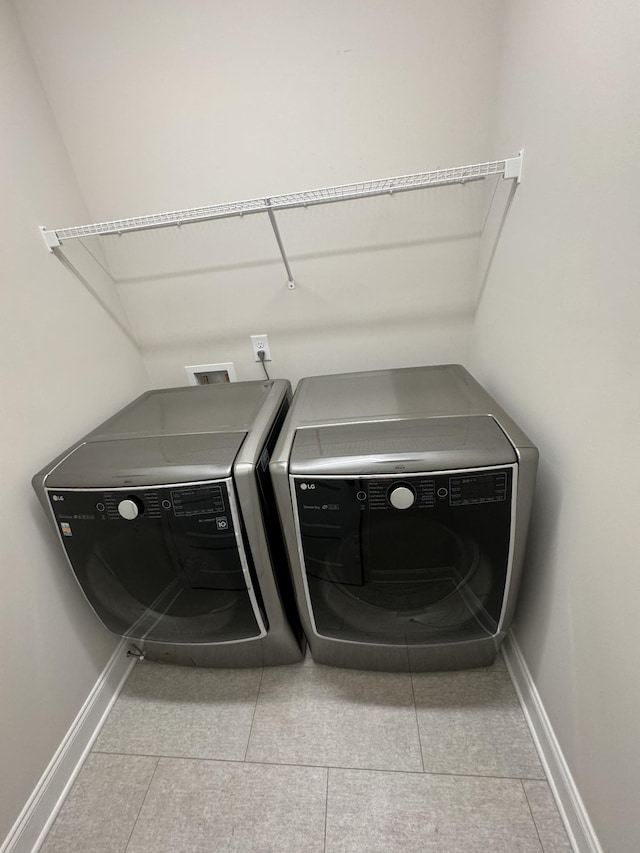 clothes washing area featuring washing machine and clothes dryer, laundry area, tile patterned floors, and baseboards