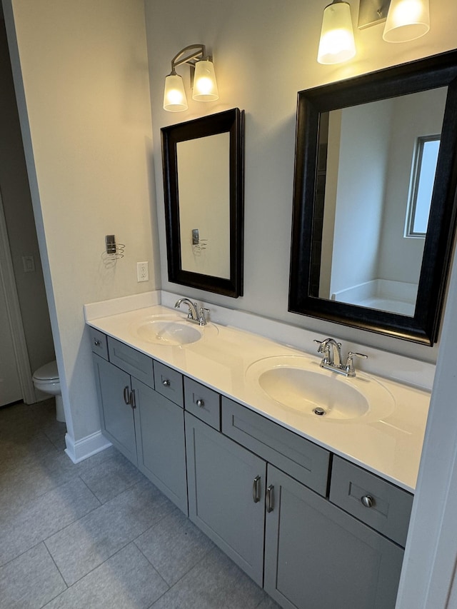 full bath with a sink, toilet, double vanity, and tile patterned floors