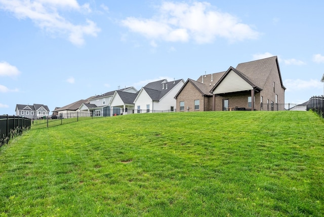 rear view of property with brick siding, a residential view, a lawn, and a fenced backyard