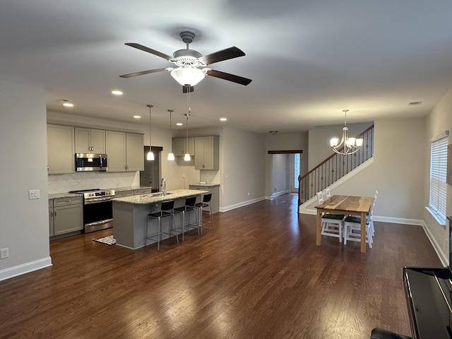 kitchen with a kitchen bar, dark wood-type flooring, gray cabinets, and appliances with stainless steel finishes