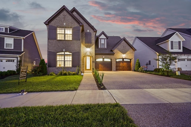 view of front of property with brick siding, a yard, driveway, and a garage