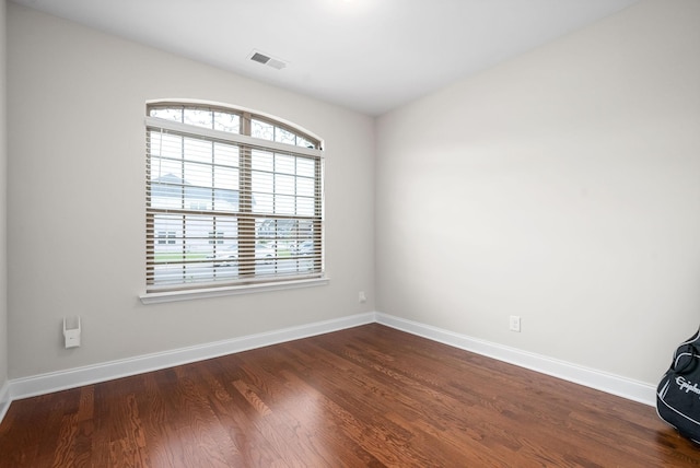 unfurnished room featuring visible vents, baseboards, and dark wood finished floors