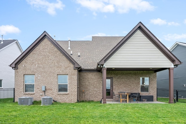 back of house featuring brick siding, a patio area, a lawn, and fence