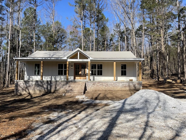 view of front of home featuring brick siding, a porch, metal roof, and board and batten siding