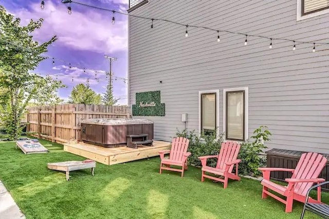 exterior space featuring a wooden deck, fence, a lawn, and a hot tub