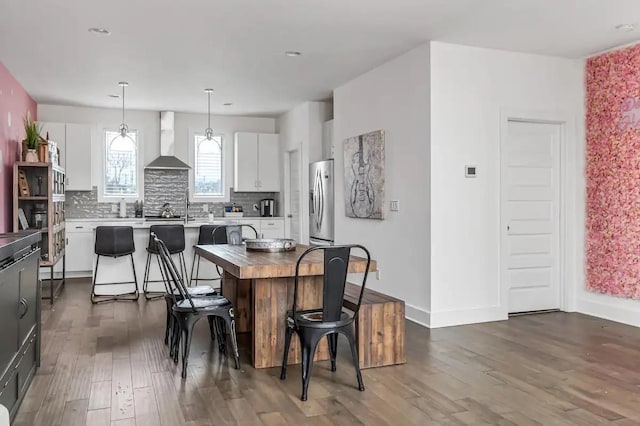 kitchen with tasteful backsplash, dark wood finished floors, freestanding refrigerator, white cabinetry, and wall chimney exhaust hood