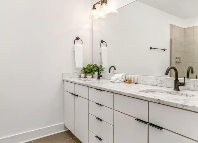 full bathroom with double vanity, baseboards, tile patterned floors, and a sink