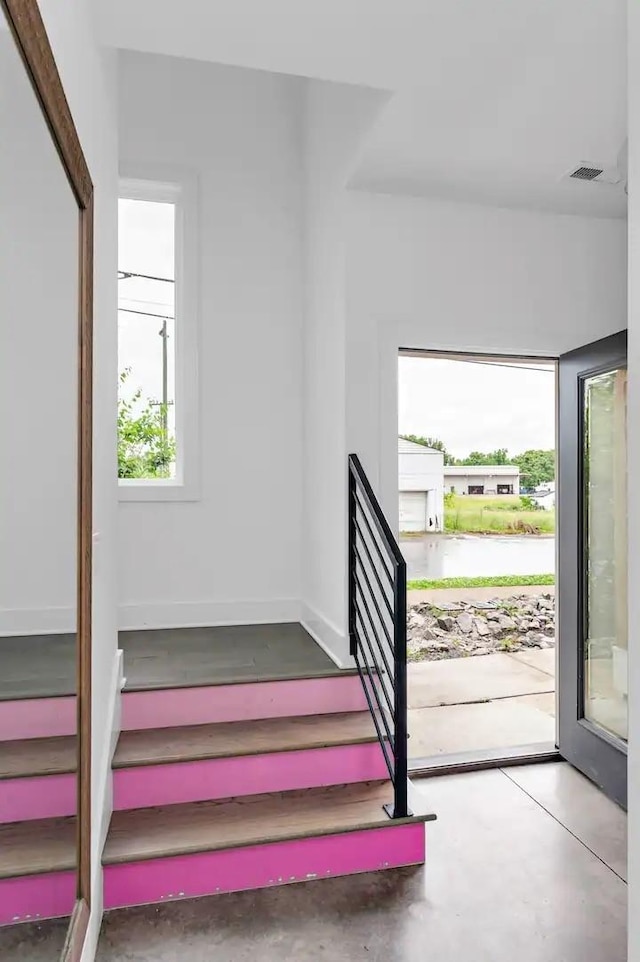 staircase featuring baseboards, visible vents, and concrete floors