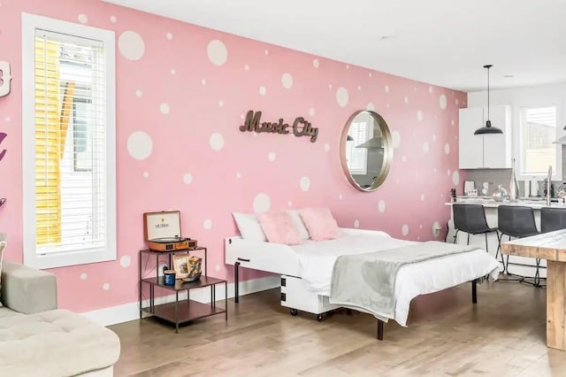 bedroom with light wood-type flooring, multiple windows, baseboards, and wallpapered walls