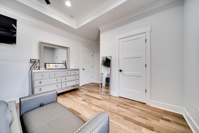 bedroom with ornamental molding, a tray ceiling, recessed lighting, light wood-style floors, and baseboards