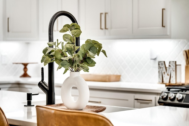 details featuring range with gas cooktop, light countertops, white cabinets, and tasteful backsplash