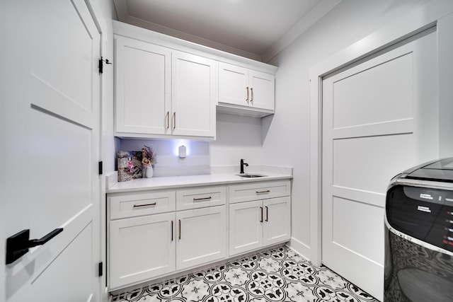 kitchen with light countertops, white cabinets, light tile patterned floors, and a sink