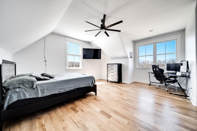 bedroom featuring light wood finished floors, a ceiling fan, baseboards, and vaulted ceiling