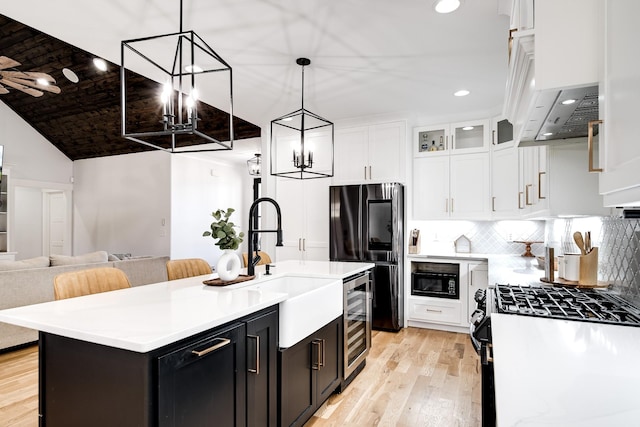 kitchen with wine cooler, black appliances, white cabinets, and light countertops