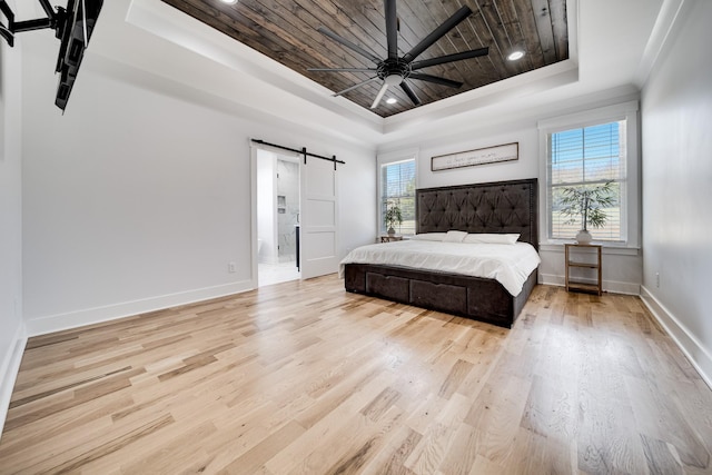 bedroom featuring baseboards, light wood-type flooring, a barn door, wooden ceiling, and a raised ceiling