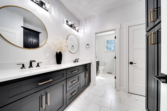 full bathroom with a sink, toilet, marble finish floor, and double vanity