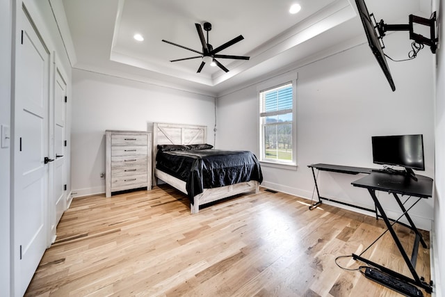 bedroom featuring recessed lighting, a tray ceiling, baseboards, and light wood-style flooring