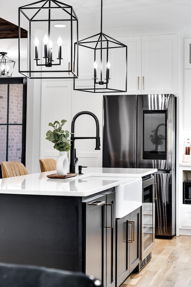 bar with light wood-style floors, wine cooler, a notable chandelier, and pendant lighting