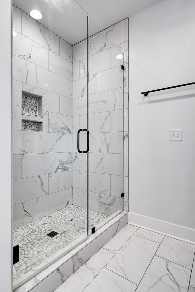 full bathroom featuring baseboards, marble finish floor, and a stall shower