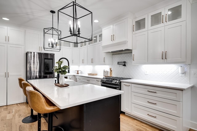 kitchen featuring extractor fan, light countertops, smart refrigerator, white cabinetry, and a center island