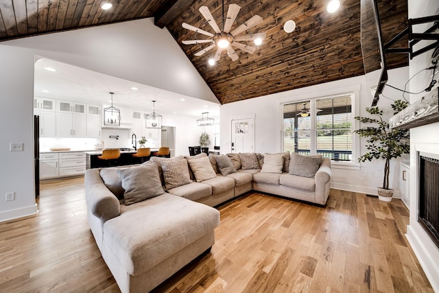 living room featuring baseboards, light wood finished floors, high vaulted ceiling, a fireplace, and wood ceiling